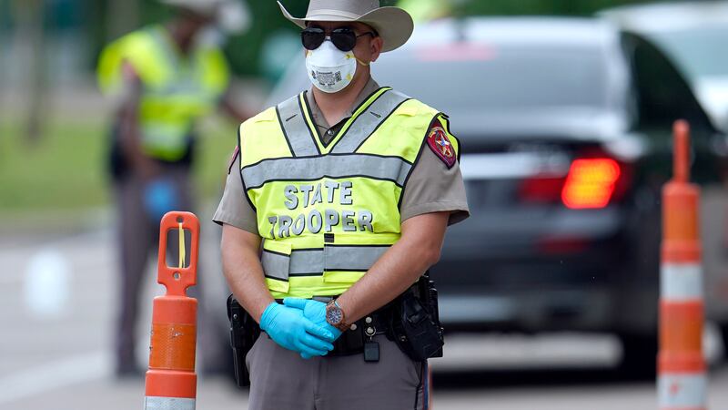 A Texas Department of Public Safety State Trooper waits to check motorists at a checkpoint in...